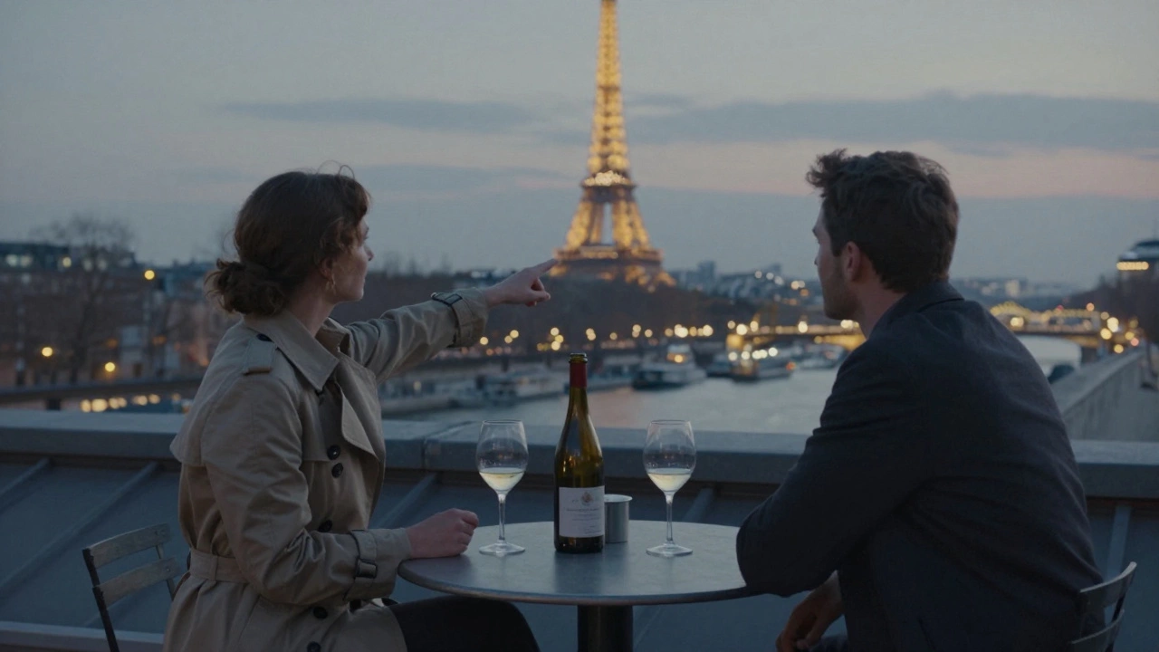 A woman and man share a quiet rooftop moment overlooking the Seine at twilight, wine glasses between them.